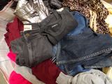 une valise pleine de vêtements et des vêtements posés sur un lit