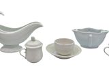 un pichet blanc, des tasses et des soucoupes posés sur une table blanche