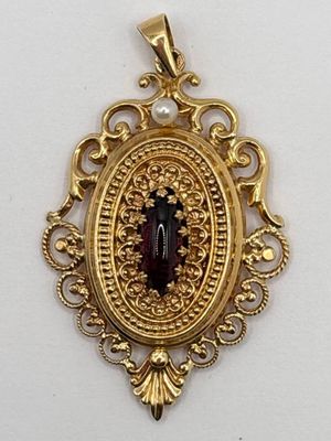 un gros plan d'un pendentif en or serti d'une pierre rouge