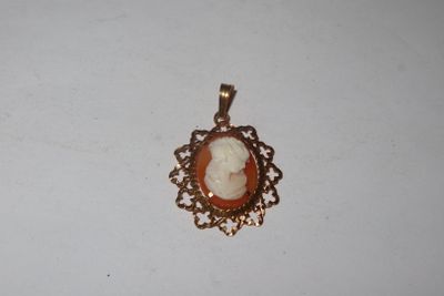 a close up of a gold pendant with a cameo of a woman