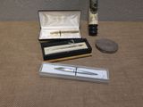 a silver pen and a silver pen in a box next to a penny
