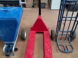 a red fork lifter sitting on the floor next to a blue hand truck