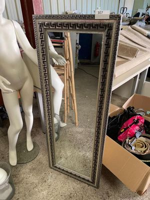 un mannequin debout près d'un miroir dans une pièce
