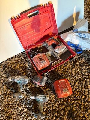une mallette rouge contenant des outils et d’autres objets, posée par terre