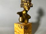 bronze bust of a woman with curly hair on a marble base
