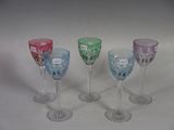 four different colored wine glasses sitting next to each other on a white surface