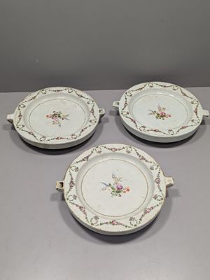 trois assiettes blanches ornées de motifs floraux sont posées sur une table