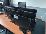 three computer monitors sitting on a desk in an office