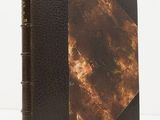 un gros plan d'un livre à la couverture marron posé sur une surface blanche