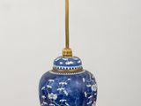 a blue and white vase with a gold handle on a wooden table