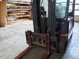 a forklift in a warehouse with pallets in the background