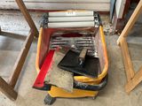 some tools are sitting on the floor next to a piece of wood