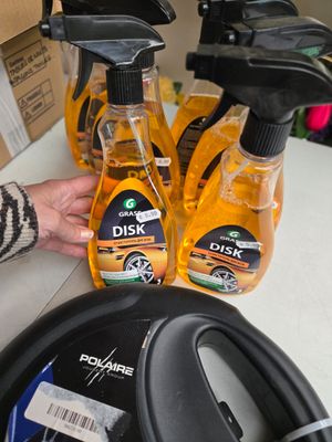 une personne tenant une bouteille de liquide vaisselle à côté de trois bouteilles de liquide vaisselle