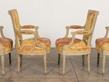 four chairs with upholstered back and arms are sitting on a wooden floor