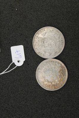 two silver coins and a silver coin with a price tag on a black surface