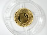 une pièce d'or représentant un cheval, posée sur une assiette transparente