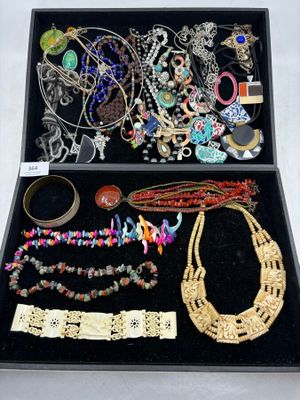 une boîte noire remplie de bijoux variés posée sur une surface blanche