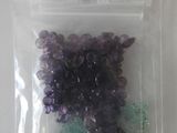 un sachet de perles violettes et vertes posé sur une table