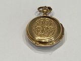 a small gold pocket watch on a white surface