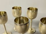 four silver goblets sitting on top of a table next to each other