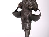une vieille statue en bronze représentant une femme tenant un arrosoir
