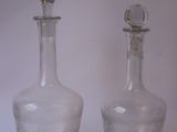 deux bouteilles en verre posées l'une à côté de l'autre sur une surface blanche