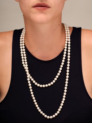 portrait of a woman wearing a pearl necklace and a black tank top