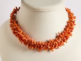 collier composé de perles de corail orange sur un mannequin blanc