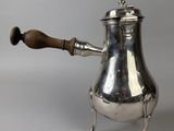 an antique silver coffee pot with a wooden handle on a stand