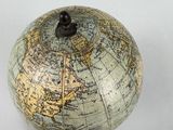 a small globe on a wooden stand on a white surface