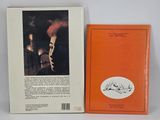 an orange book sitting next to an orange book with a picture of a woman