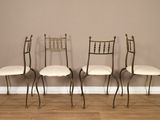 trois chaises en métal avec des coussins blancs sont adossées à un mur marron