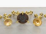 three brass candlesticks and a clock on a table