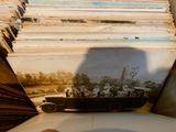 a stack of old photos on a table with a person holding a cell phone