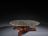 une table avec un plateau en marbre posé sur un piètement en bois, sur fond noir