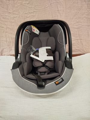 un siège auto pour bébé posé sur un lit, avec un livre à l'intérieur