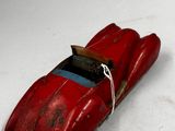 une petite voiture rouge posée sur une surface blanche