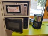 two microwaves and a coffee maker on a green table