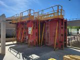 un chantier de construction avec un bâtiment rouge et des échafaudages jaunes