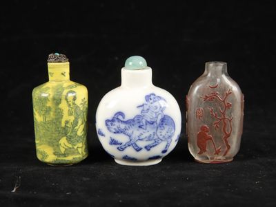 three different colored glass bottles sitting next to each other on a black surface