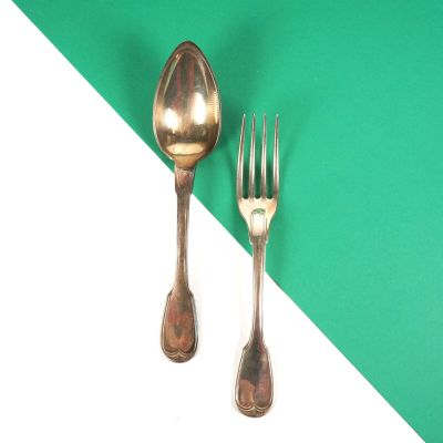 deux cuillères en argent et une fourchette sur un fond vert et blanc