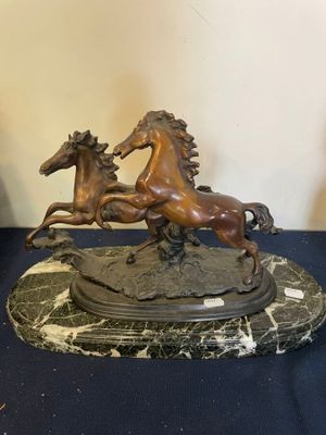 statue représentant deux chevaux, posée sur un socle en marbre, elle-même posée sur une table