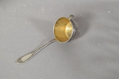 une cuillère en argent avec un manche en or posée sur une table