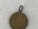 an old bronze medal is sitting on a white surface