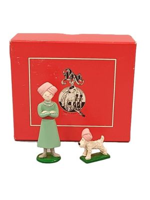 une petite figurine représentant une femme et un chien devant une boîte rouge