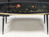 une photo d'une table basse noire et dorée sur laquelle sont disposées des fleurs
