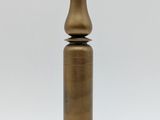 an antique brass bottle on a wooden base