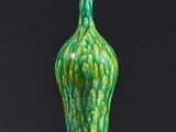 a green vase sitting on a table with a black background