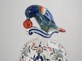 a bird sitting on top of a bowl with a lid