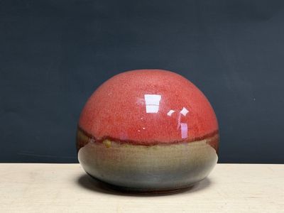 un vase rouge et marron posé sur une table en bois